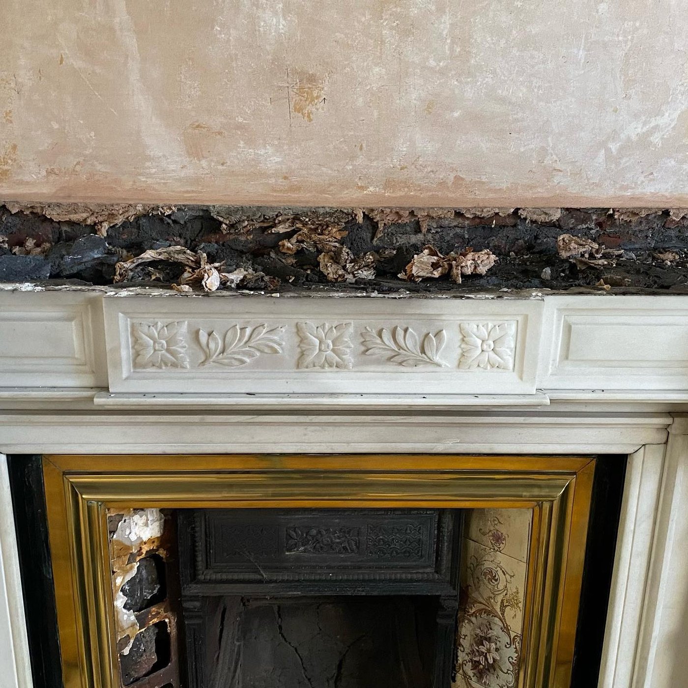 The marble fireplace, partially exposed before removal