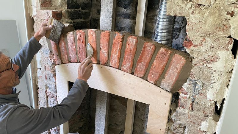 Brick arch being rebuilt over a fireplace
